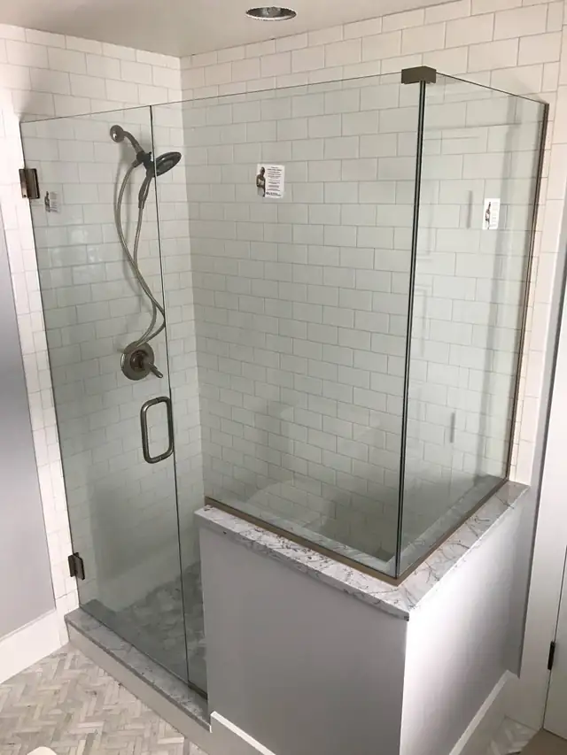 Frameless glass corner shower with white subway tile and a tiled bench ledge