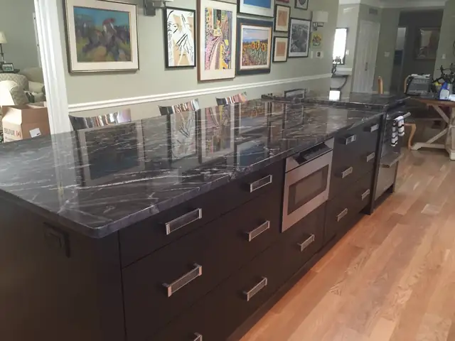 South Lyon, MI kitchen with dark espresso cabinets, a long black granite island and stainless wall ovens