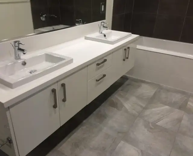 Bathroom with a floating white double vanity, square vessel-style sinks and large gray floor tile