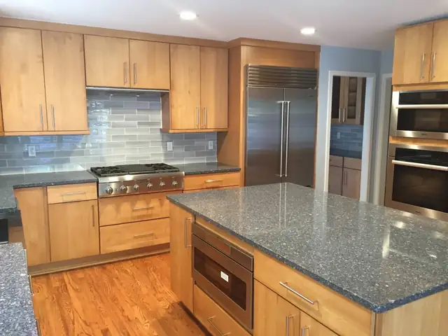 Novi, MI kitchen renovation with maple cabinets, a blue-gray quartz island, stainless built-in refrigerator and hardwood floors