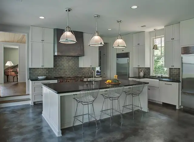 Birmingham, MI kitchen with white cabinets, an island with wire stools, three industrial pendant lights and recessed ceiling lights